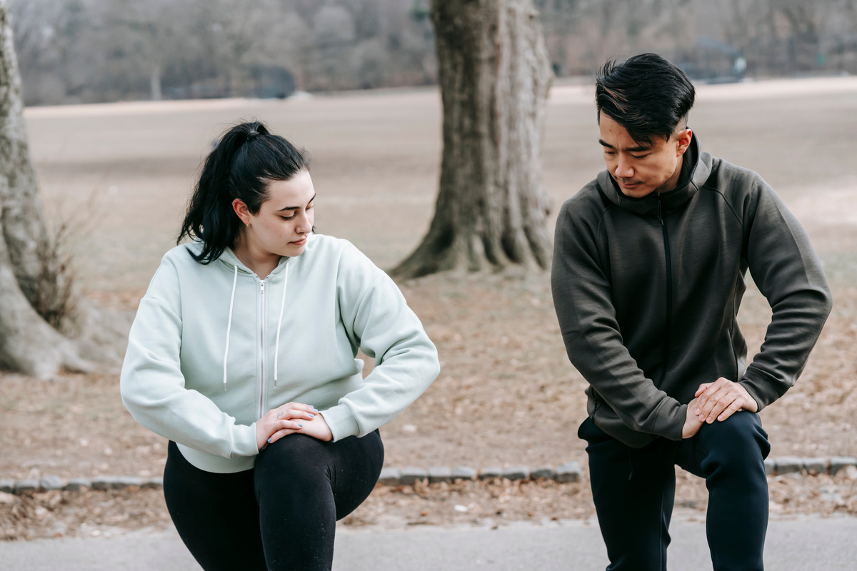 Plus sized woman training with Asian man in park